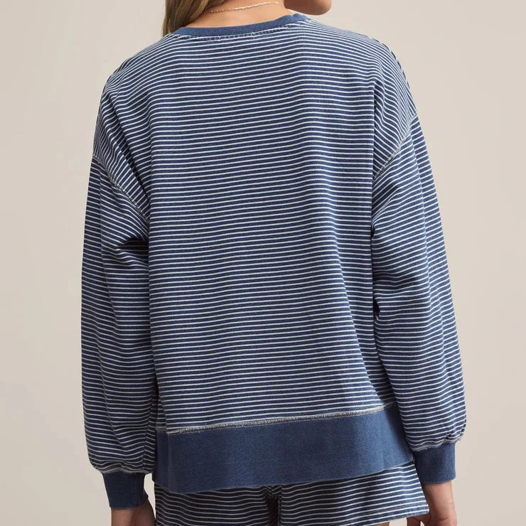 Woman wearing a blue striped sweater and shorts set on a beige background