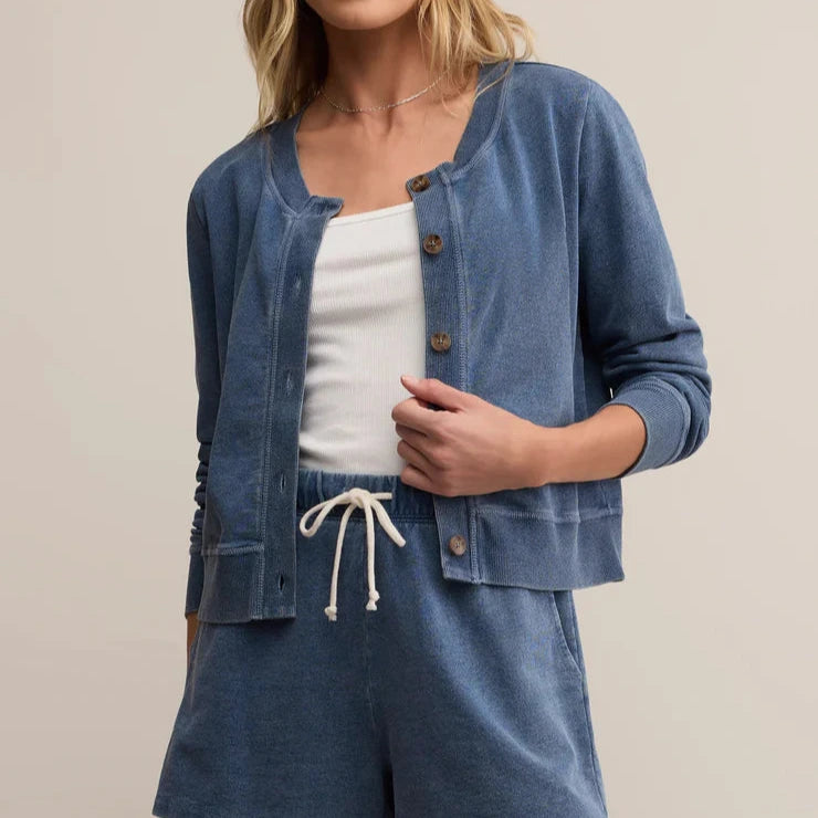 Woman wearing a blue denim cardigan and shorts set on a beige background